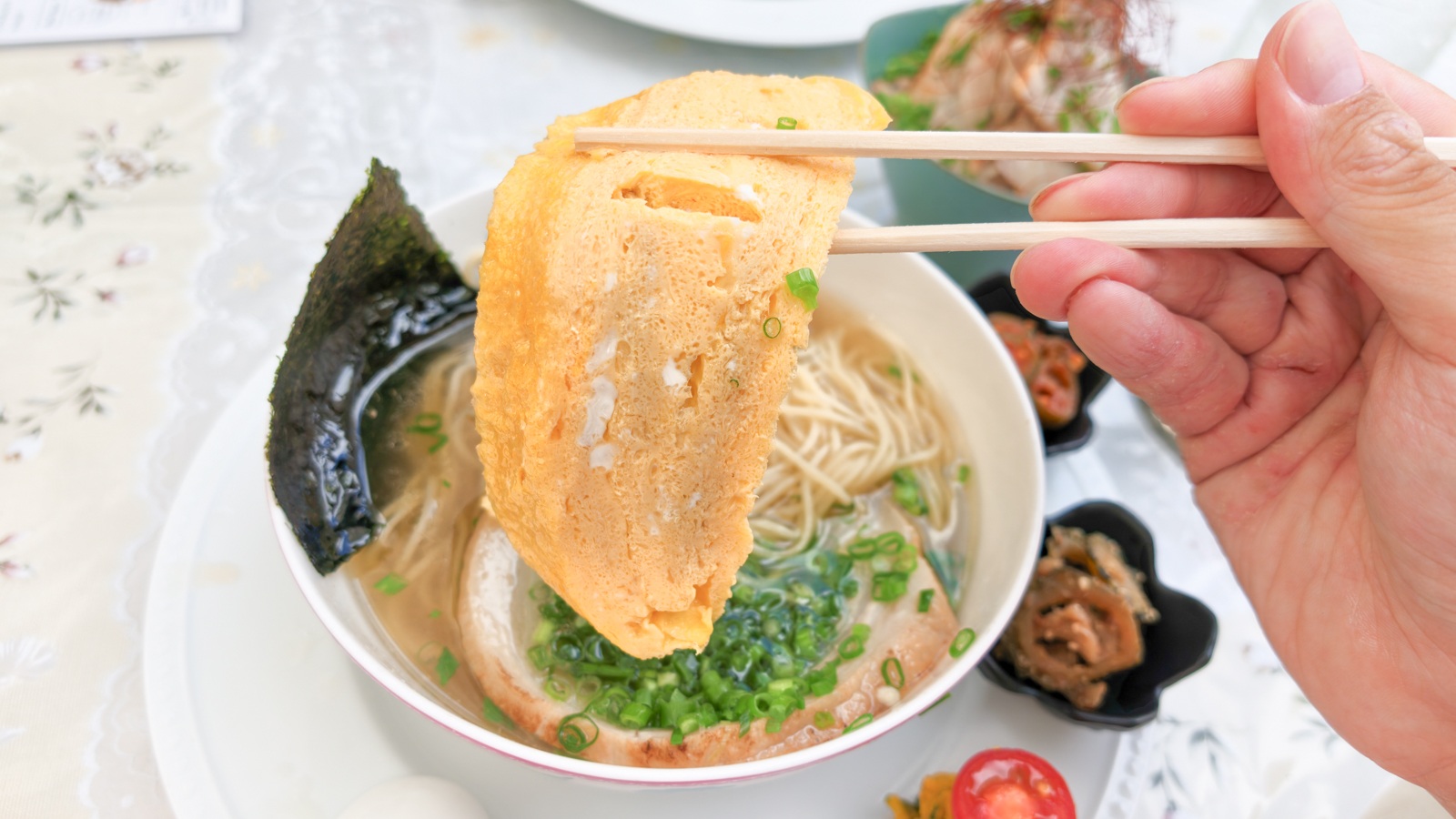 坂のうえチャーシュー麺の大きな卵焼きを箸で持ち上げた様子