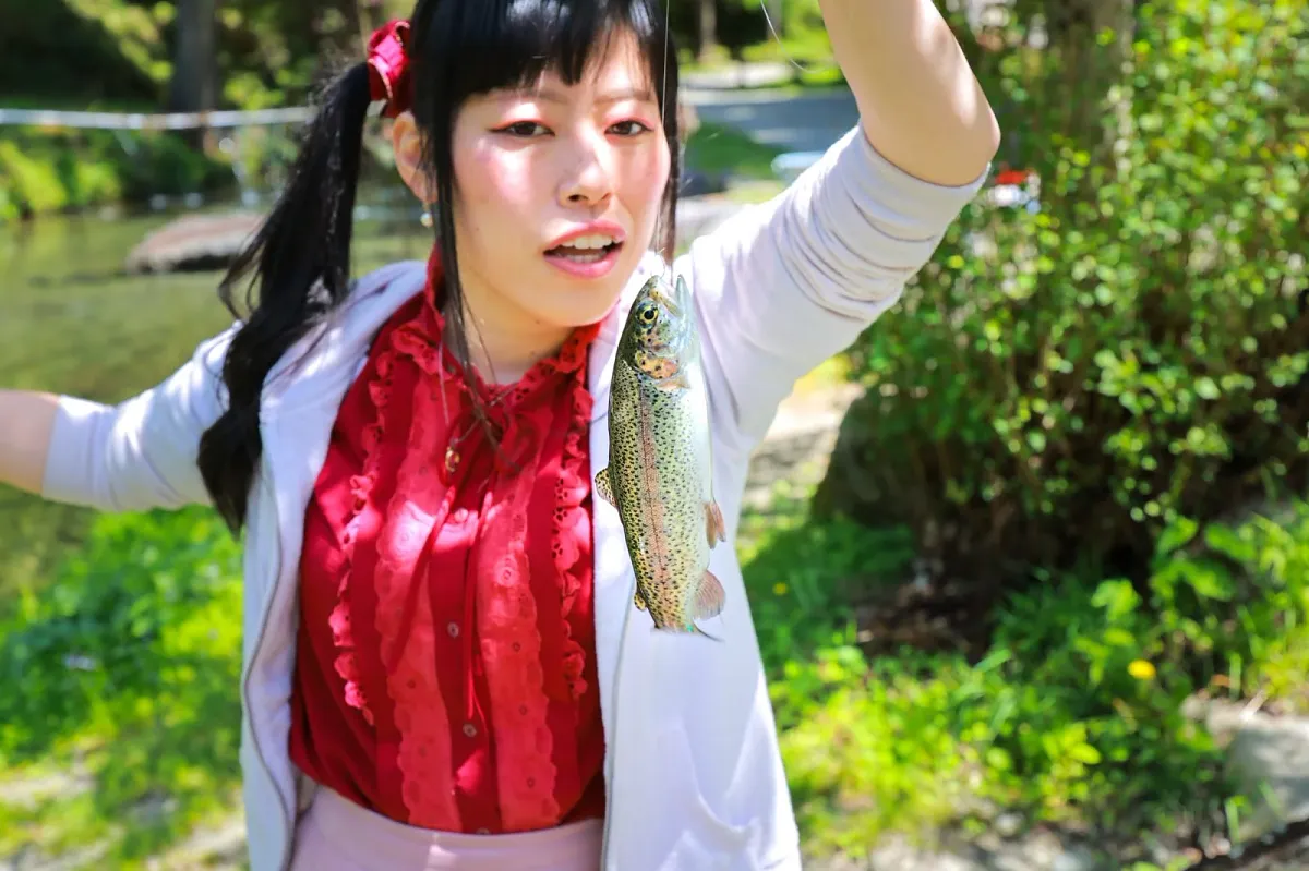 釣り上げたニジマスを手にする来場者